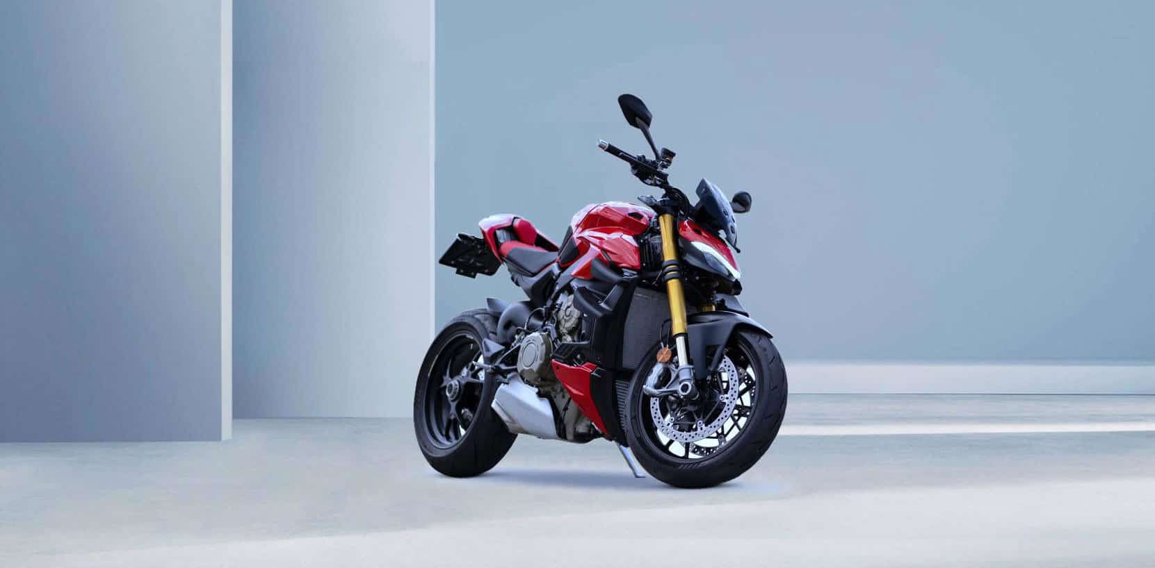 Red and black sports motorcycle in a clean pale blue studio.