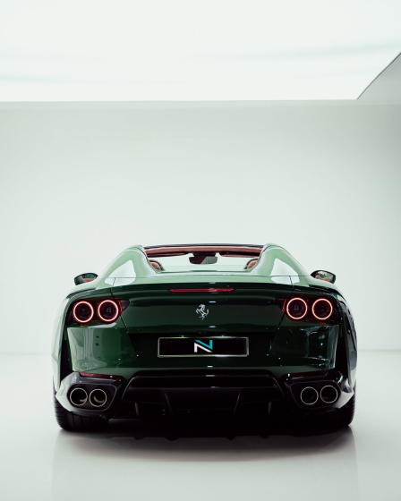 Rear view of a green Ferrari in a white studio