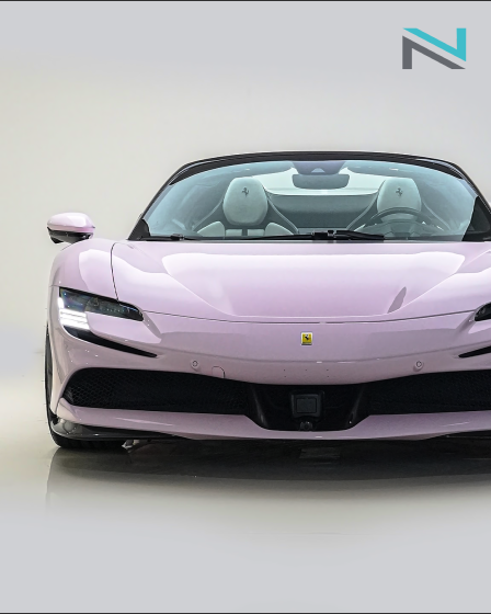 Pale pink sports car photographed from the front in a white studio